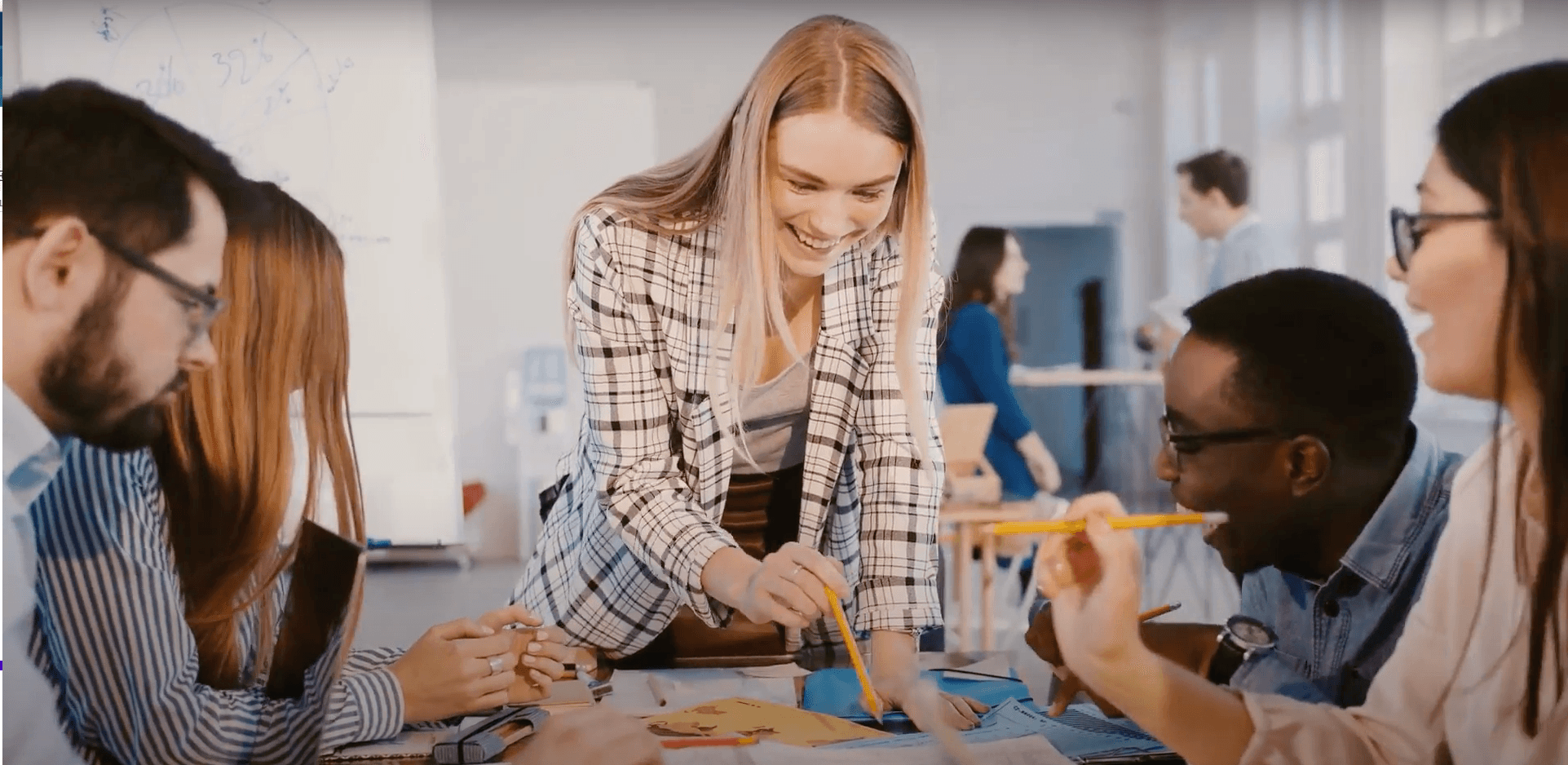 Een enthousiaste vrouw illustreert haar unieke persoonlijke skills met een potlood, terwijl aandachtige collega's toekijken in een creatieve kantooromgeving