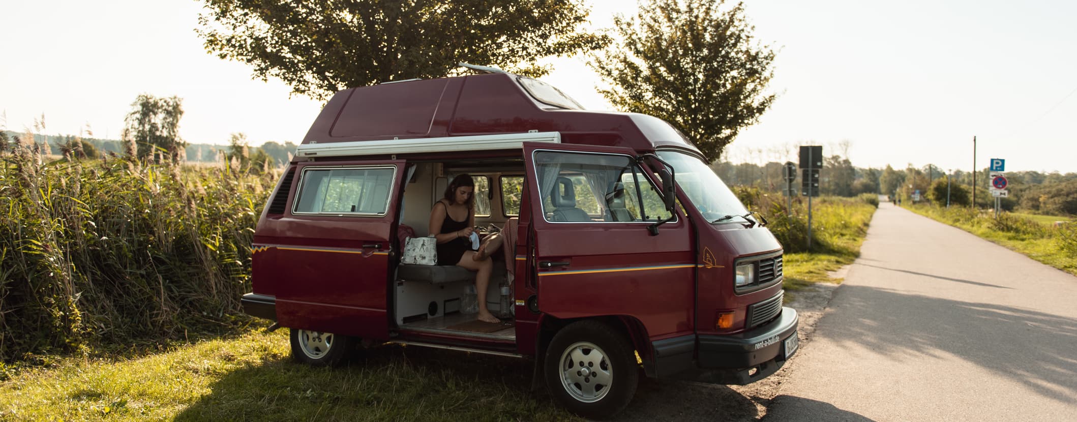 Een vrouw zit ontspannen in een camper omringd door een groene omgeving het vrije beeld van dat gemeenschap van de NKC haar leden biedt