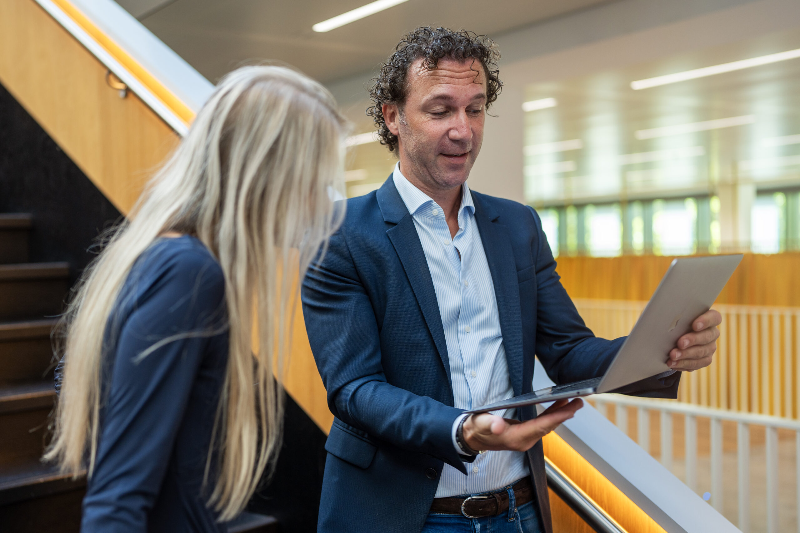 Financieel administratief medewerker toont belangrijke gegevens op zijn laptopscherm aan een collega