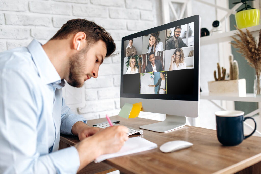 Man werkt achter zijn computer in een online meeting met vieze vaat naast hem buiten beeld van de camera