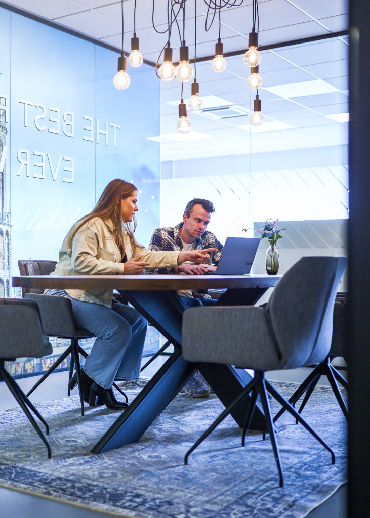 collega's zitten samen te werken in vergaderruimte. Collega bedenkt dat die een andere baan wilt