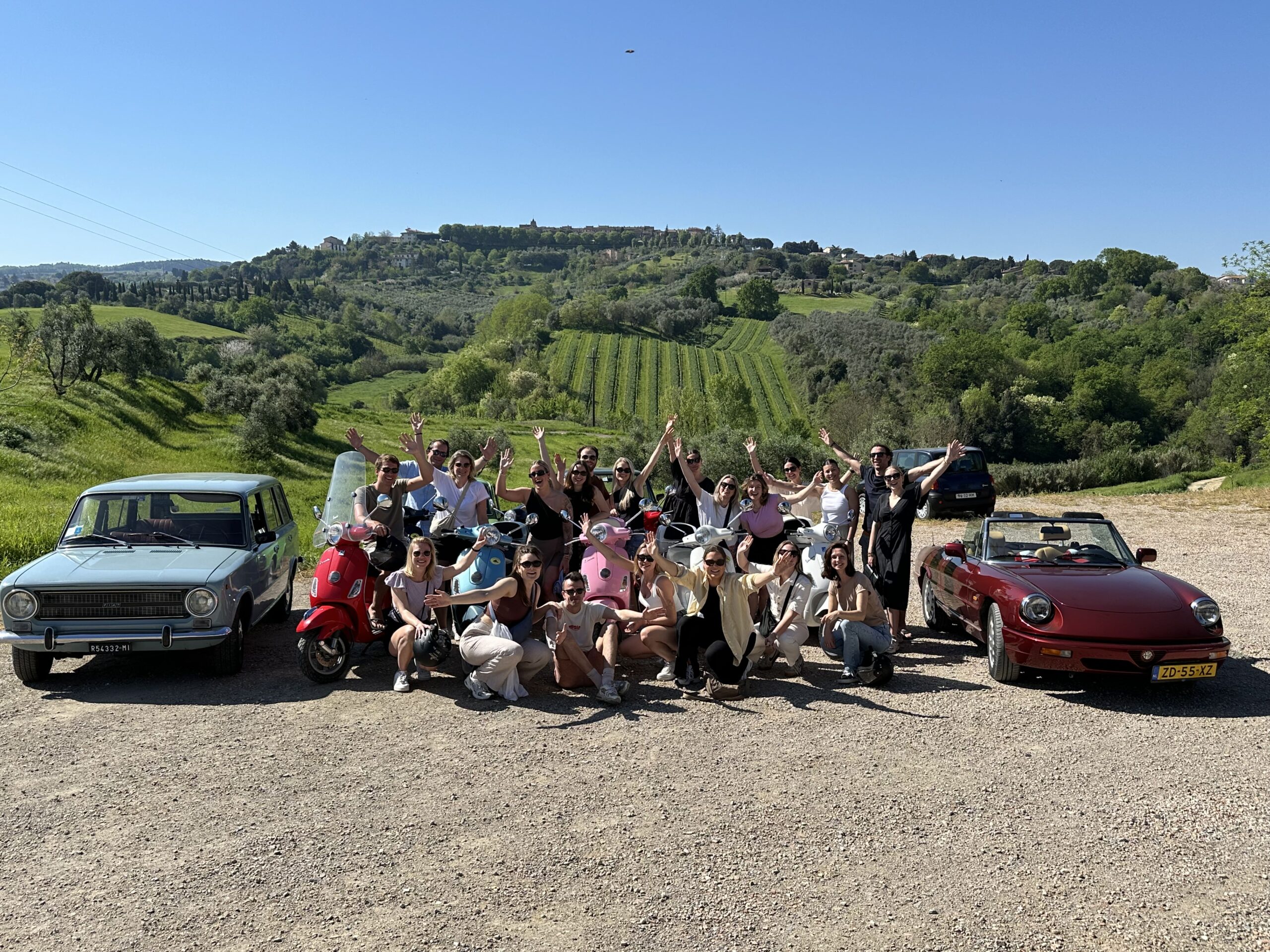 Alle medewerkers van Work-on juichen tussen 2 oldtimers in Toscane, Italië.